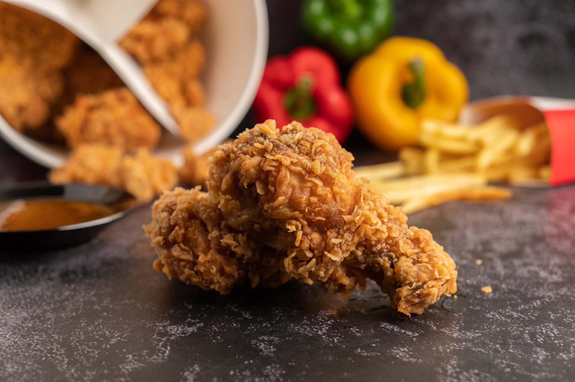 Fried Chicken and French Fries on Black Cement Floor.